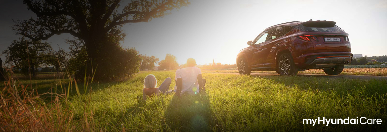 Hyundai Tucson color rojo junto a un árbol al atardecer